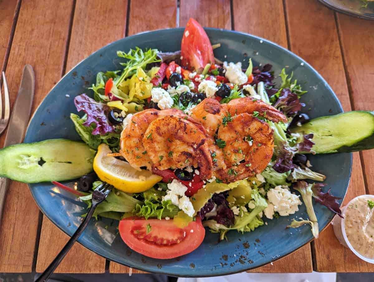 A greek "Athena" salad with blackened shrimp skewer on top