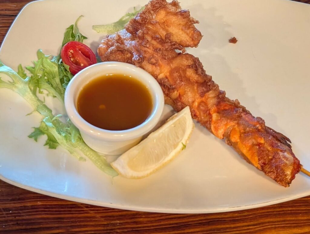Tempura lobster tail on a skewer with dipping sauce and lemon at Boat House Bar and Grill in Key West