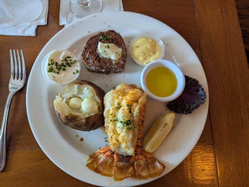 Overhead view of a lobster tail and filet mignon with baked potato and drawn butter at Duffy's Steak and Lobster House in Key West