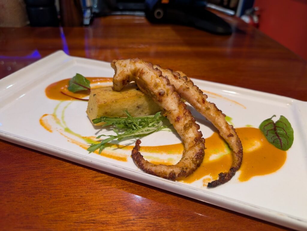 Wood grilled octopus with applewood bacon polenta and dried tomato vinaigrette.