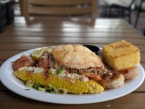 Lobster tail, grilled shrimp, corn, red potatoes and cornbread on a white plate at the Key West Lobsterfest Lobster Boil